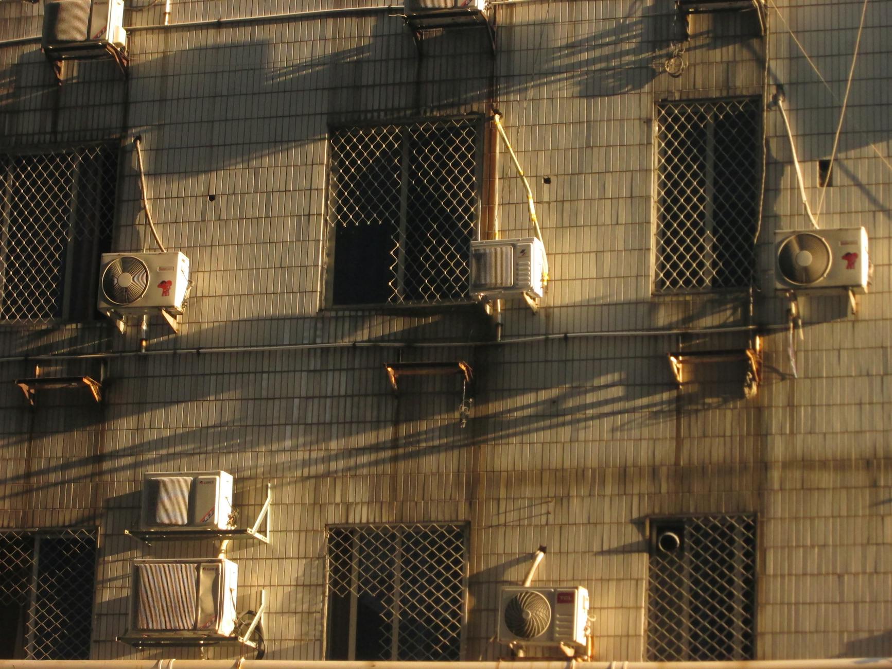 Miejska elewacja z klimatyzatorami i grą światła na fasadzie budynku