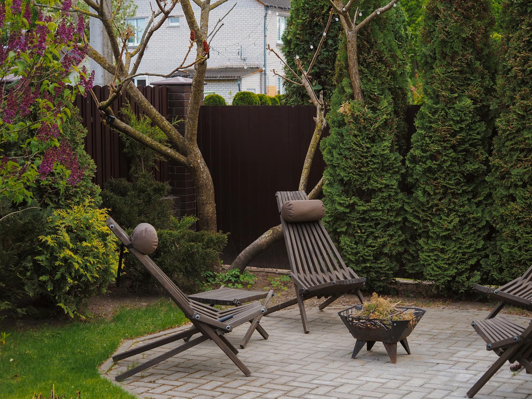 Przytulny mały taras z drewnianymi leżakami otoczony bujną zielenią