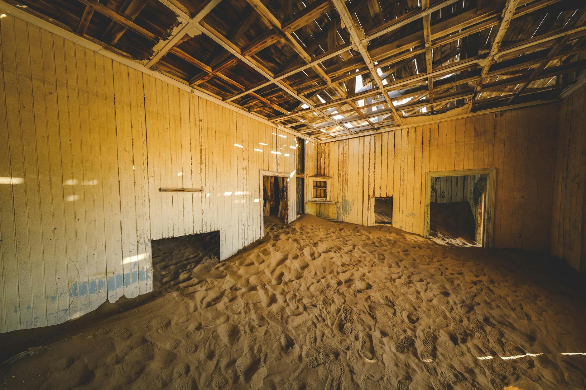 Opuszczony pokój w słońcu z podłogą drewnianą zasypaną piaskiem