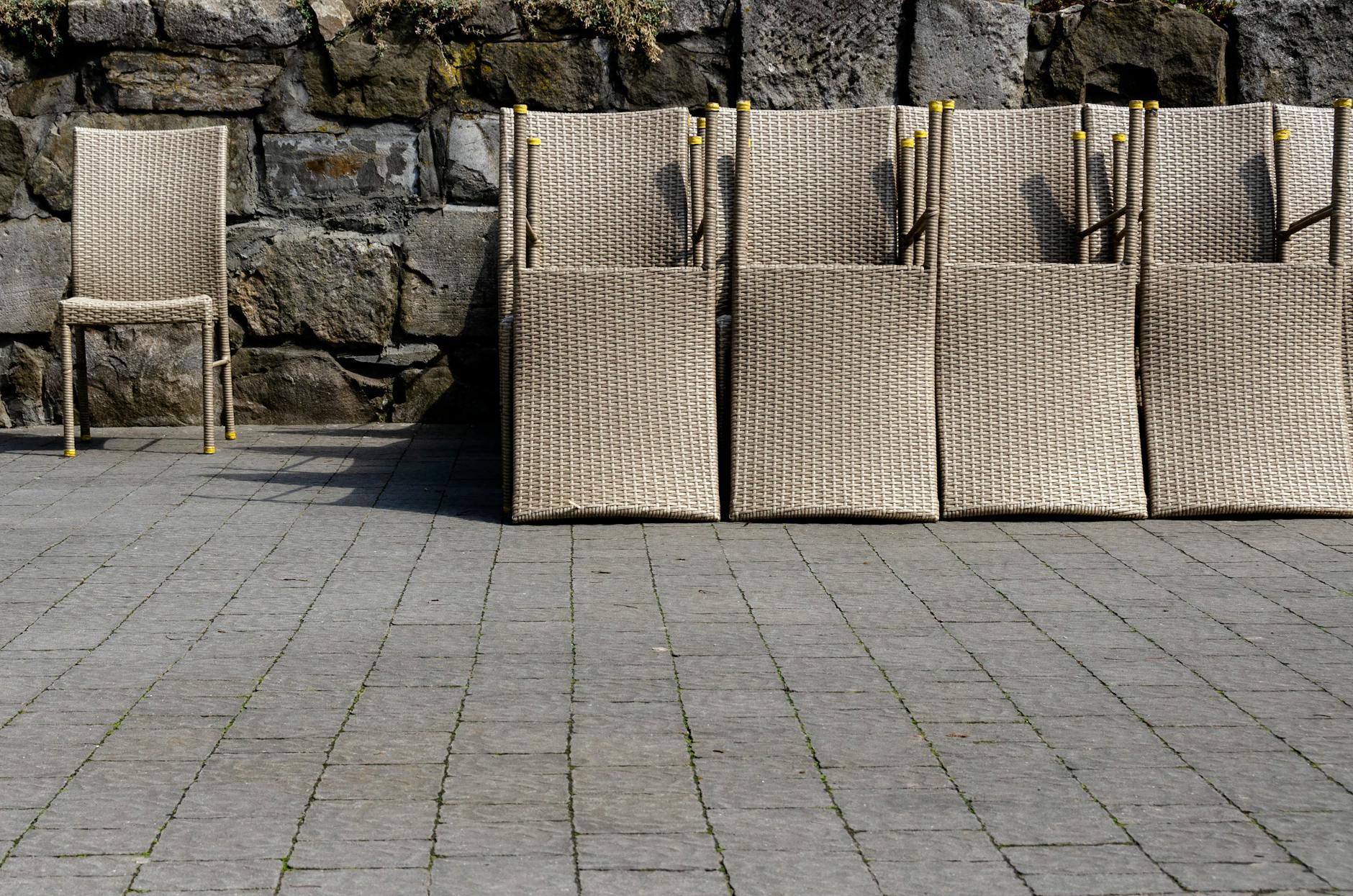 Wiklinowe krzesła ogrodowe na tle kamiennego muru
