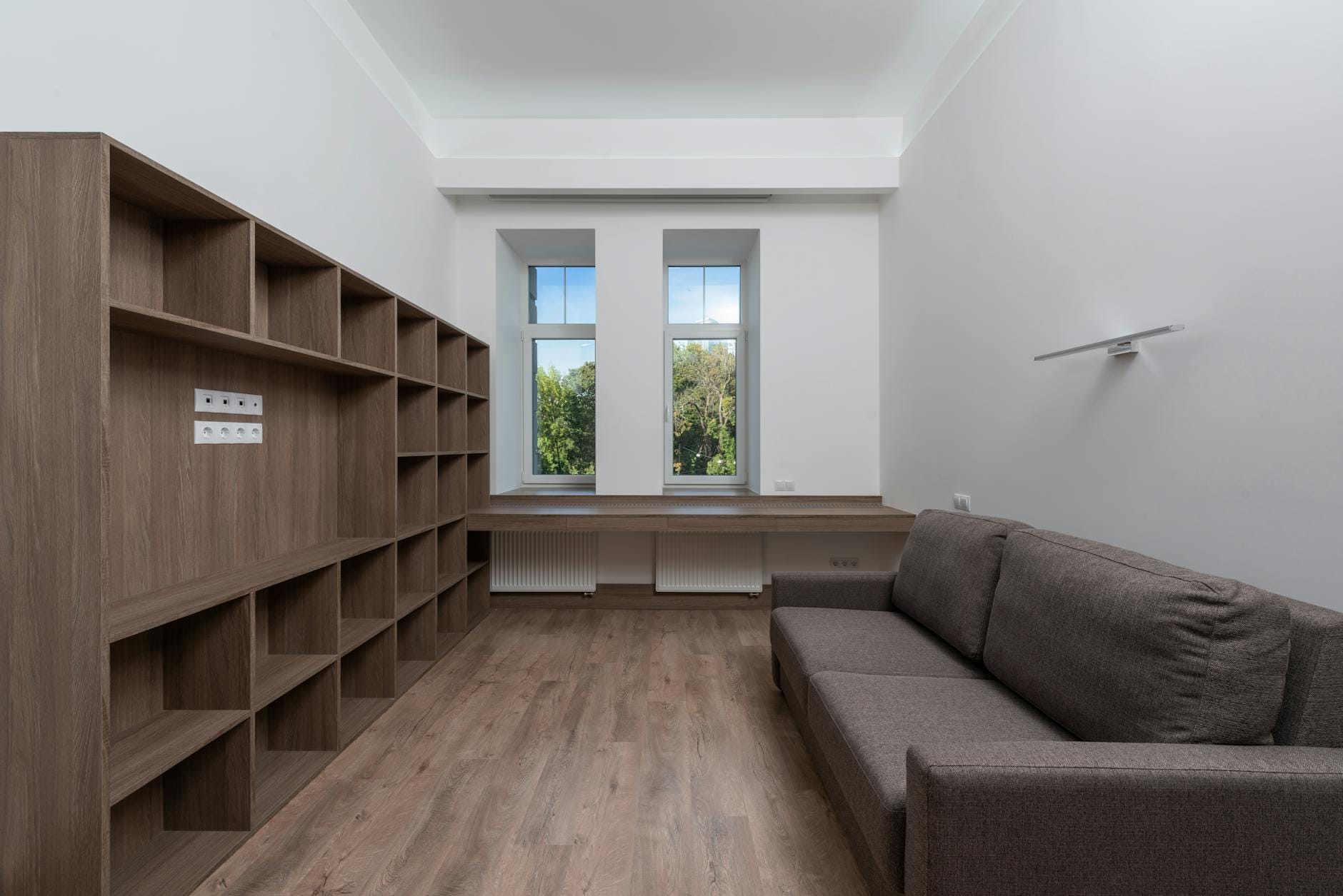 Nowoczesny salon z drewnianą podłogą, półkami i dużymi oknami