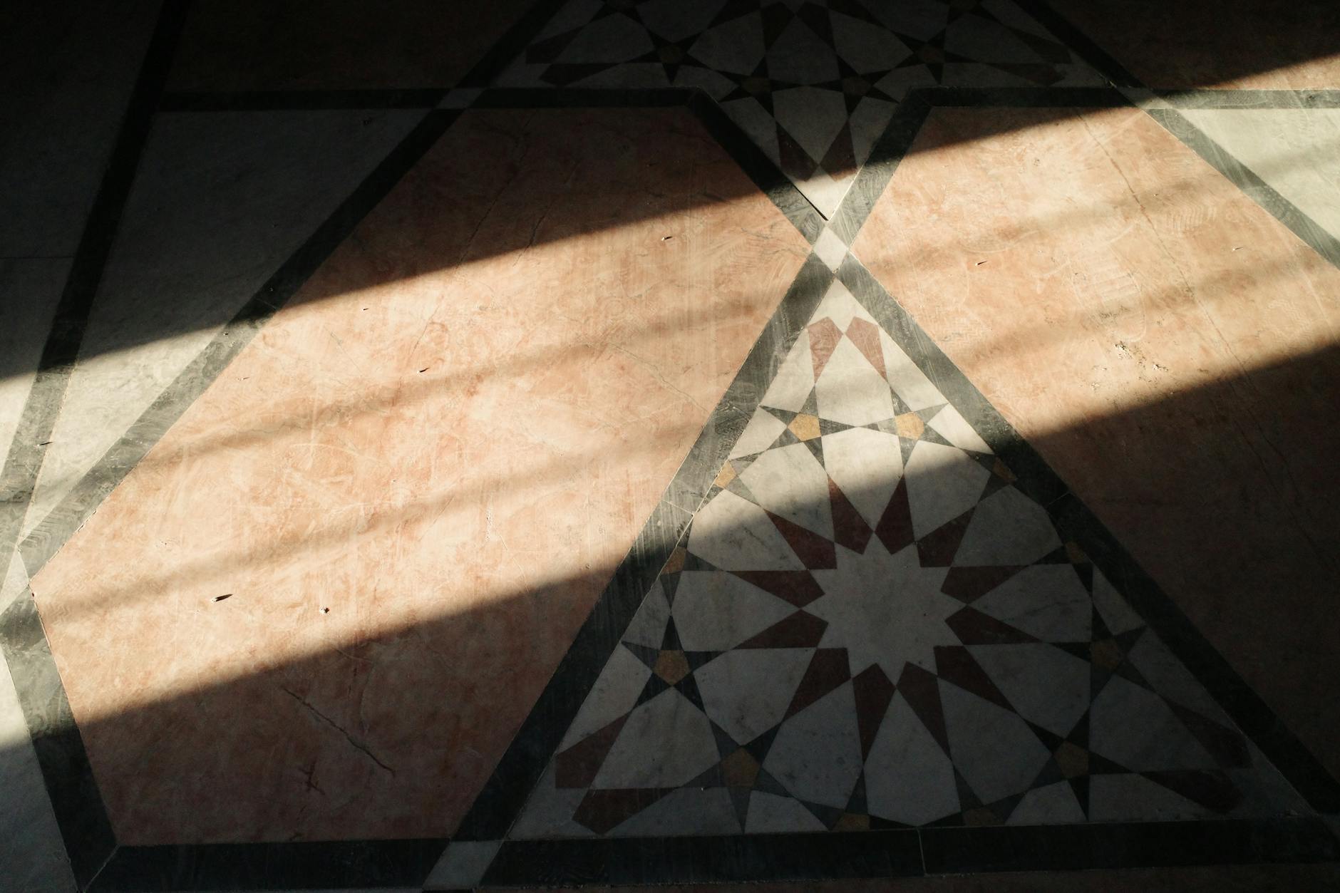 Słońce rzuca geometryczne cienie na podłogę z płytek w Aleppo